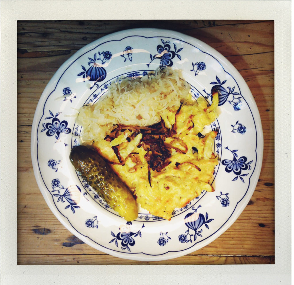 Teller mit Sauerkraut, Kartoffelpuffer und Essiggurke