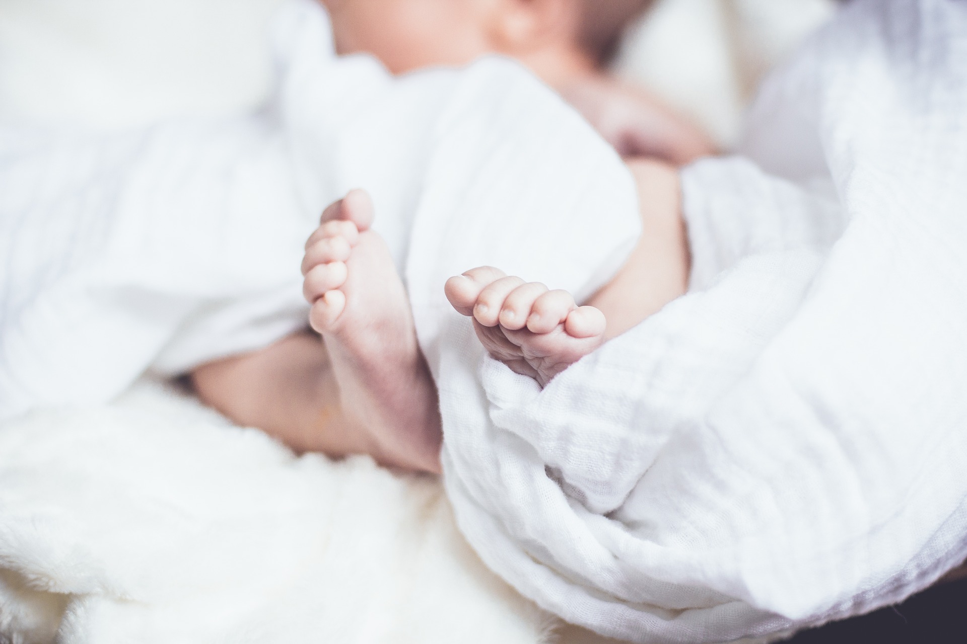 Nakte Babyfüße eingewickelt in einem Moltontuch