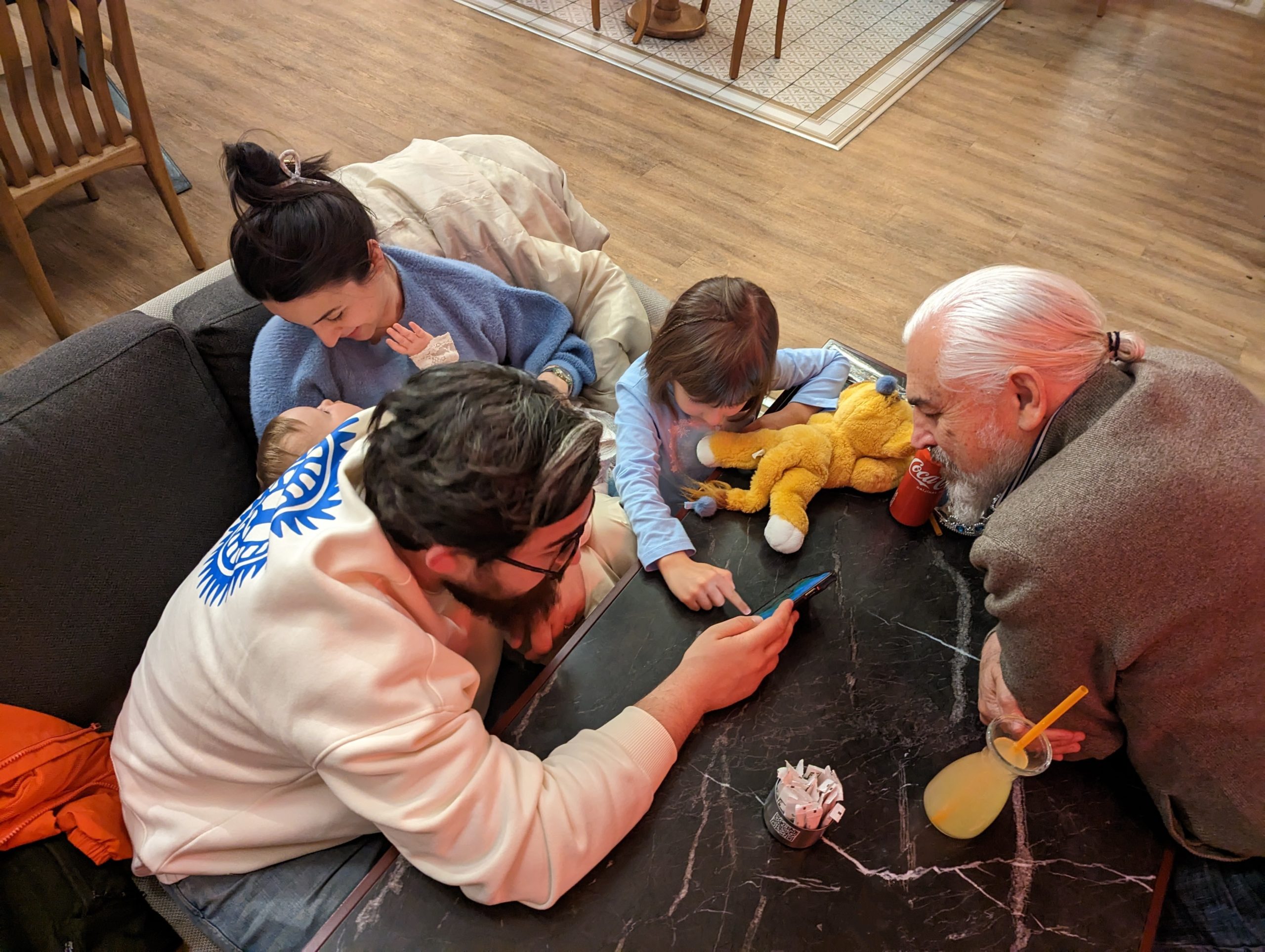 Familie sitzt im Restaurant und schaut sich Fotos auf dem Handy an
