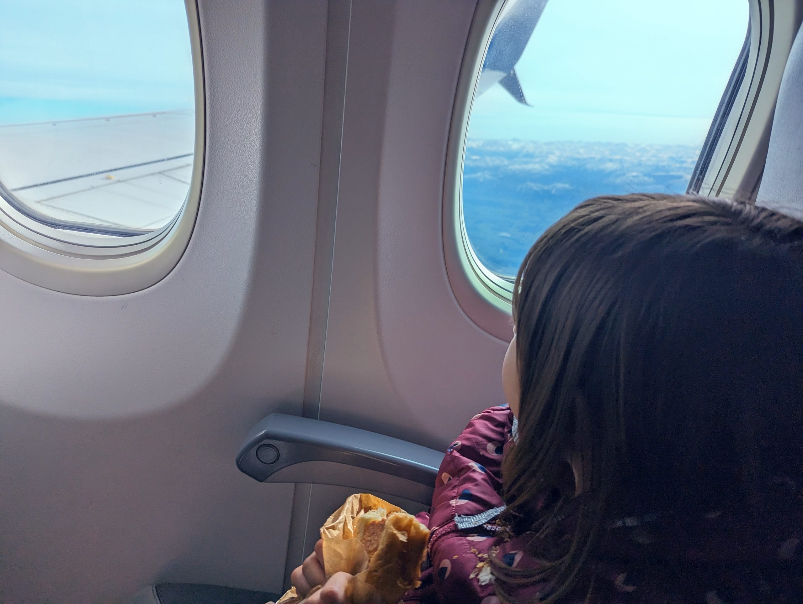 Mädchen schaut aus Fenster im Flugzeug