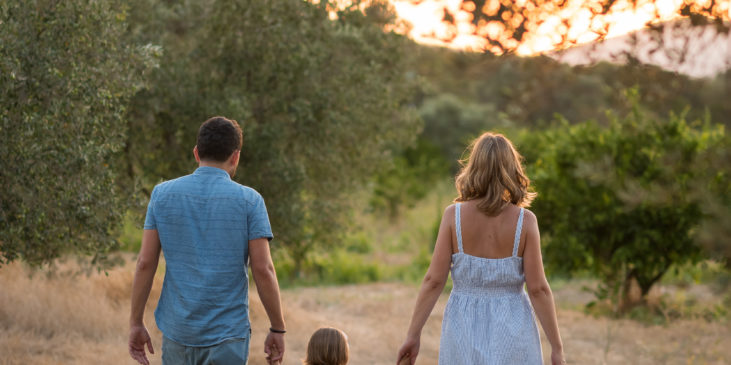 Mutter, Vater und Kind Hand in Hand auf einem Feldweg