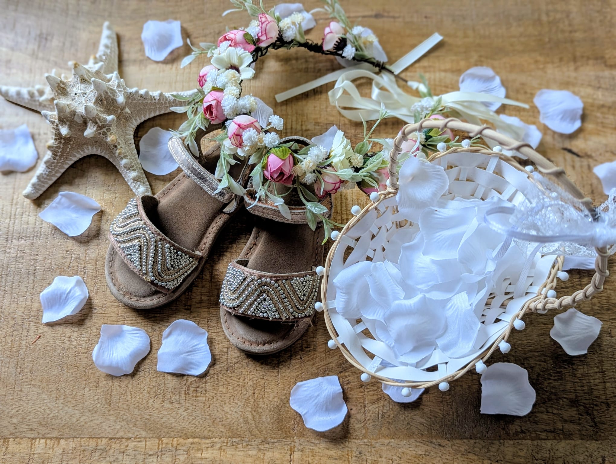 Erinnerung an unsere Strandhochzeit in der Türkei: goldene Kindersandalen, ein Blütenkranz für die Blumenkinder und ein kleiner Korb voller weißer Rosenblätter